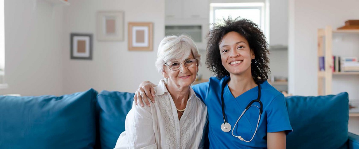 A caring home healthcare professional assisting an elderly patient in their living room.