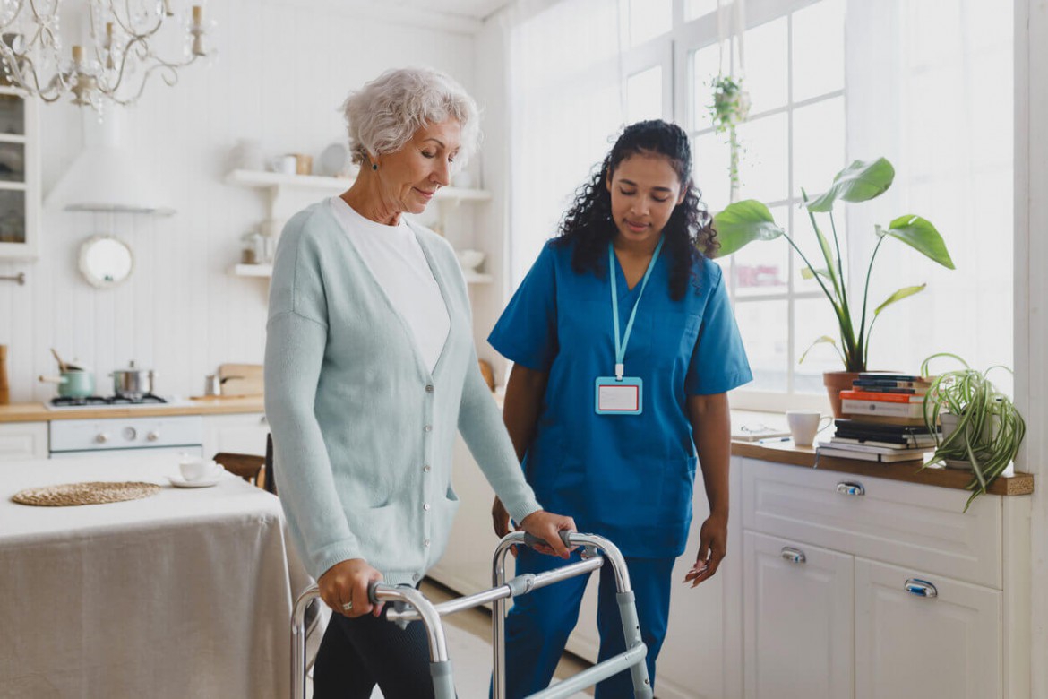 Nurse assisting a patient with physical therapy during post-hospitalization recovery at home.